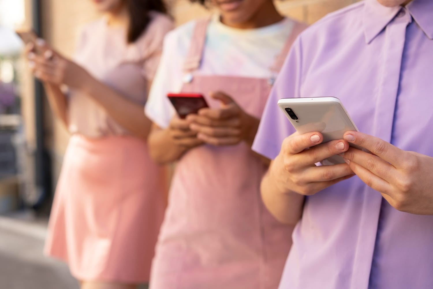 3 people in an apron, shirts, and blouse are playing with their phones.