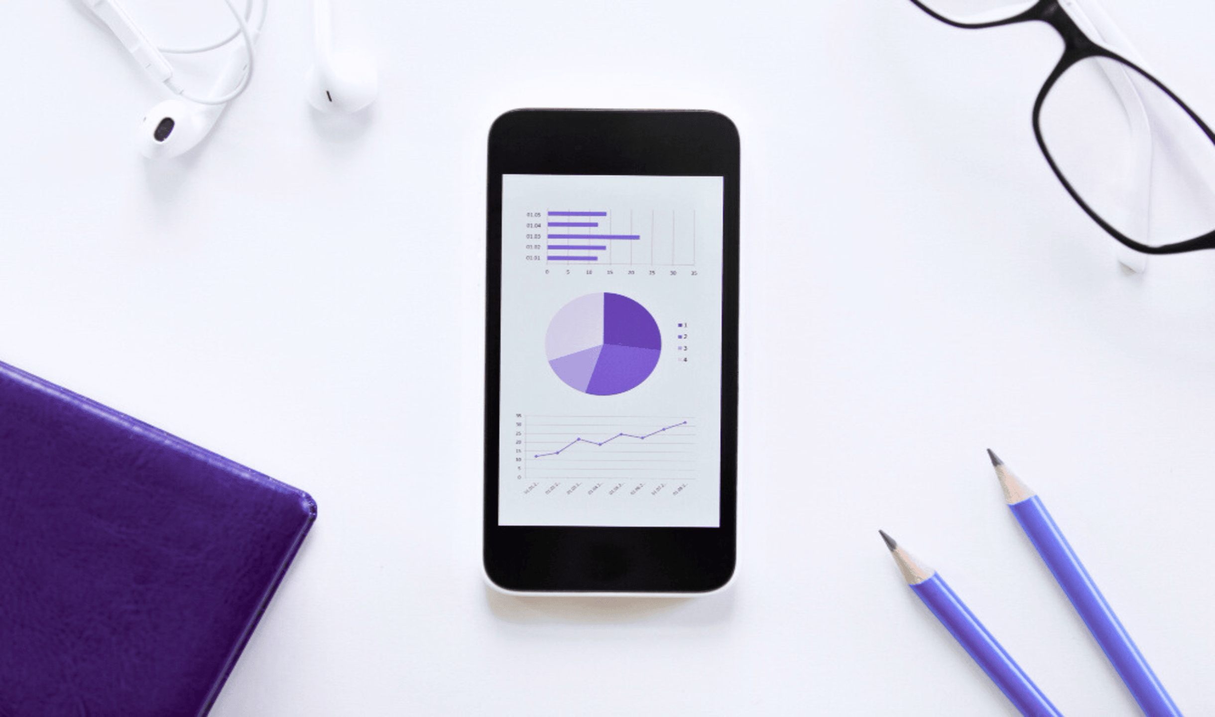 An image showing a mobile phone with a push notification performance chart, pencils, notebook, and glasses